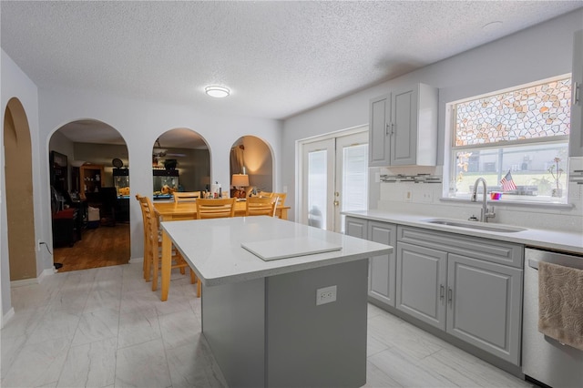 3216 White Blossom Ln, Clermont, FL 34711 - kitchen with dishwasher, gray cabinetry, a center island, arched walkways, and light countertops