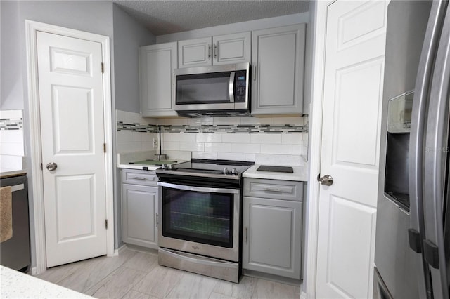 3216 White Blossom Ln, Clermont, FL 34711 - kitchen with stainless steel appliances, gray cabinets, light countertops, tasteful backsplash, and a textured ceiling