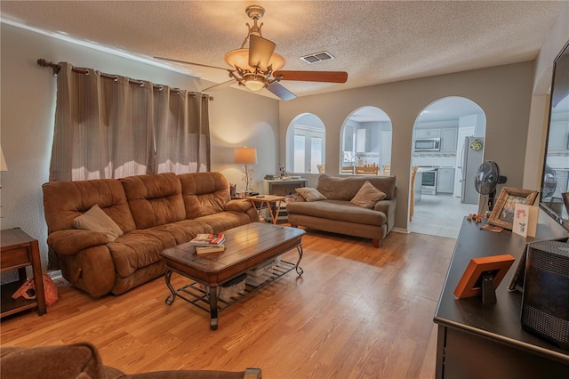 3216 White Blossom Ln, Clermont, FL 34711 - living area featuring arched walkways, light wood-type flooring, ceiling fan, and a textured ceiling