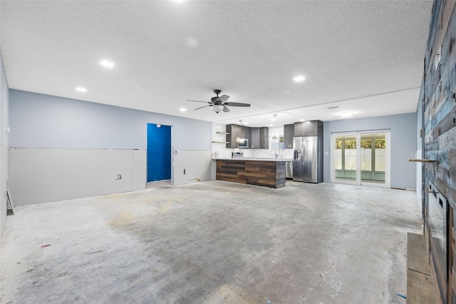 2302 16th St W, Palmetto, FL 34221 - unfurnished living room with concrete flooring, a textured ceiling, recessed lighting, ceiling fan, and a fireplace