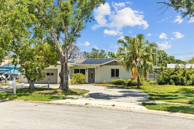 2302 16th St W, Palmetto, FL 34221 - view of front of home featuring driveway, stucco siding, a garage, roof mounted solar panels, and a front lawn