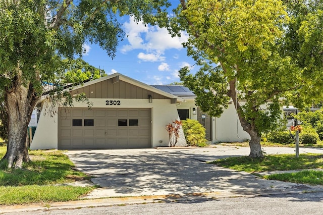 2302 16th St W, Palmetto, FL 34221 - view of front facade with a garage, roof mounted solar panels, concrete driveway, and stucco siding