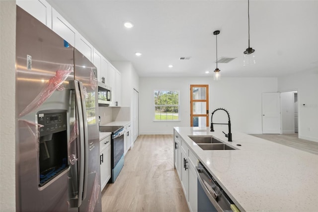 3072 SW 168th Loop, Ocala, FL 34473 - kitchen with appliances with stainless steel finishes, a sink, light wood-style flooring, white cabinetry, and light stone countertops