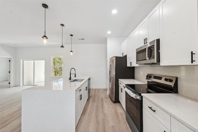 3072 SW 168th Loop, Ocala, FL 34473 - kitchen with stainless steel appliances, a sink, light wood-style flooring, backsplash, and a kitchen island with sink