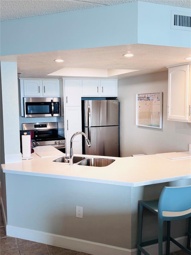 4453 S Atlantic Ave Unit 602, Ponce Inlet, FL 32127 - kitchen featuring stainless steel appliances, a sink, a peninsula, white cabinetry, and a kitchen bar