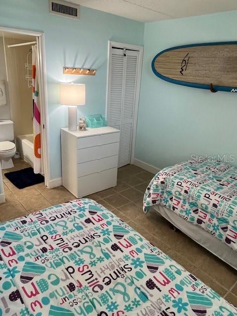 4453 S Atlantic Ave Unit 602, Ponce Inlet, FL 32127 - bedroom with light tile patterned floors, a closet, ensuite bath, and baseboards
