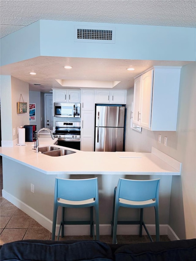 4453 S Atlantic Ave Unit 602, Ponce Inlet, FL 32127 - kitchen featuring appliances with stainless steel finishes, a peninsula, a sink, white cabinets, and a textured ceiling