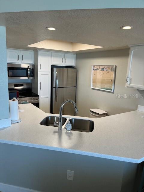 4453 S Atlantic Ave Unit 602, Ponce Inlet, FL 32127 - kitchen featuring stainless steel appliances, a sink, white cabinetry, recessed lighting, and a textured ceiling