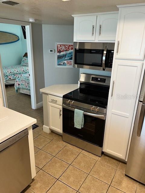 4453 S Atlantic Ave Unit 602, Ponce Inlet, FL 32127 - kitchen with stainless steel appliances, light tile patterned floors, white cabinets, and light countertops