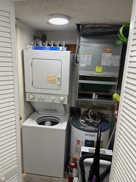 4453 S Atlantic Ave Unit 602, Ponce Inlet, FL 32127 - washroom featuring stacked washing machine and dryer, a textured ceiling, and electric water heater