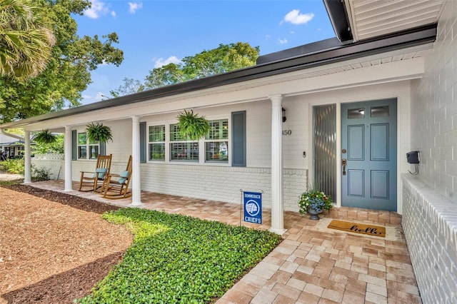 property entrance featuring a porch and brick siding