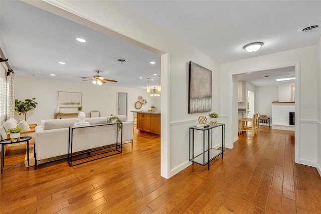 living area featuring a ceiling fan, light wood-style flooring, a fireplace, baseboards, and recessed lighting