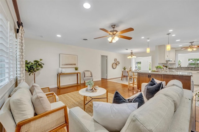 living area with ceiling fan, recessed lighting, light wood-type flooring, and baseboards