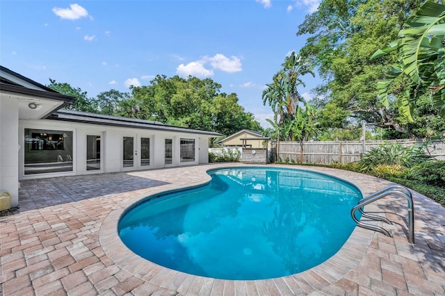 view of pool with a patio, a fenced backyard, and french doors