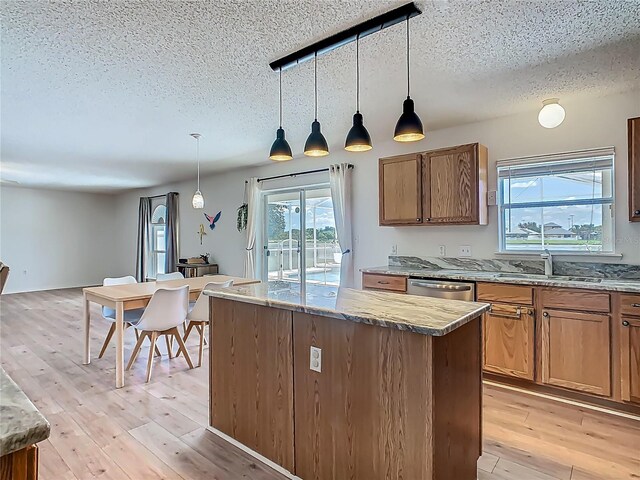 2384 Andrews Valley Dr, Kissimmee, FL 34758 - kitchen featuring a sink, a textured ceiling, a center island, light wood finished floors, and decorative light fixtures