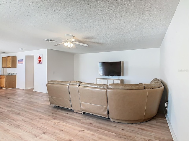 2384 Andrews Valley Dr, Kissimmee, FL 34758 - living room with a textured ceiling, light wood-style flooring, ceiling fan, and baseboards