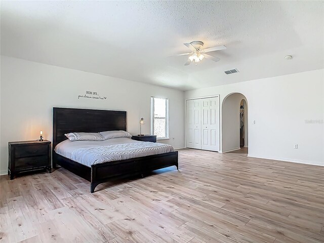 2384 Andrews Valley Dr, Kissimmee, FL 34758 - bedroom featuring arched walkways, light wood finished floors, baseboards, a ceiling fan, and a textured ceiling