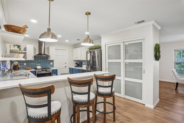 921 Torchwood Dr, Deland, FL 32724 - kitchen featuring stainless steel appliances, wall chimney exhaust hood, crown molding, blue cabinets, and a sink