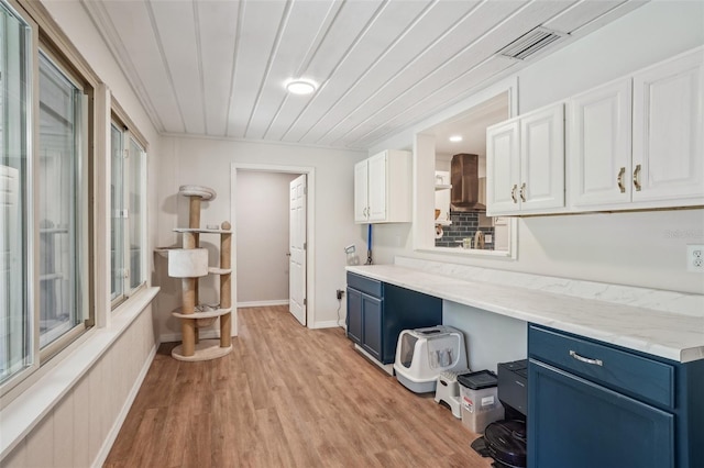 921 Torchwood Dr, Deland, FL 32724 - kitchen with blue cabinets, wall chimney range hood, white cabinetry, and light wood finished floors