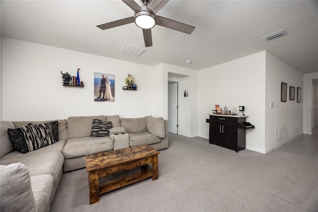 living area with ceiling fan, light colored carpet, a textured ceiling, and baseboards