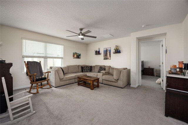 living room featuring a ceiling fan, light colored carpet, baseboards, and a textured ceiling
