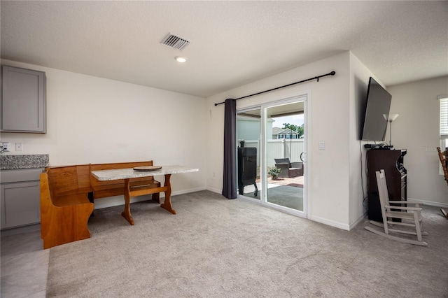 dining area with healthy amount of natural light, baseboards, a textured ceiling, and light colored carpet