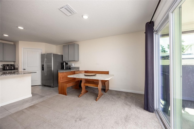 kitchen featuring stainless steel refrigerator with ice dispenser, gray cabinets, plenty of natural light, light colored carpet, and recessed lighting