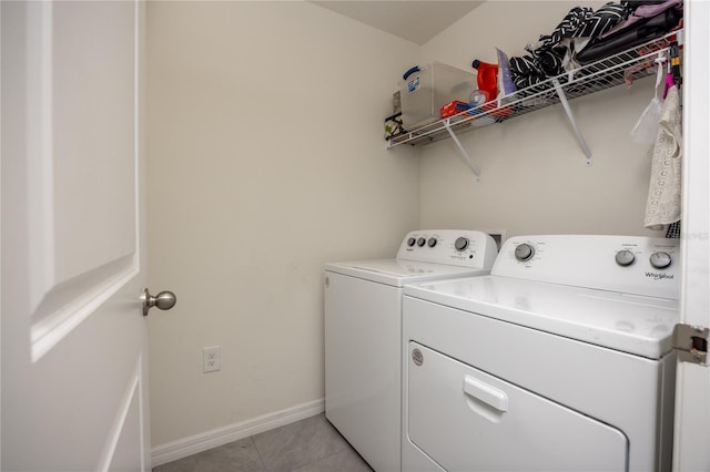 clothes washing area with separate washer and dryer, light tile patterned floors, and baseboards