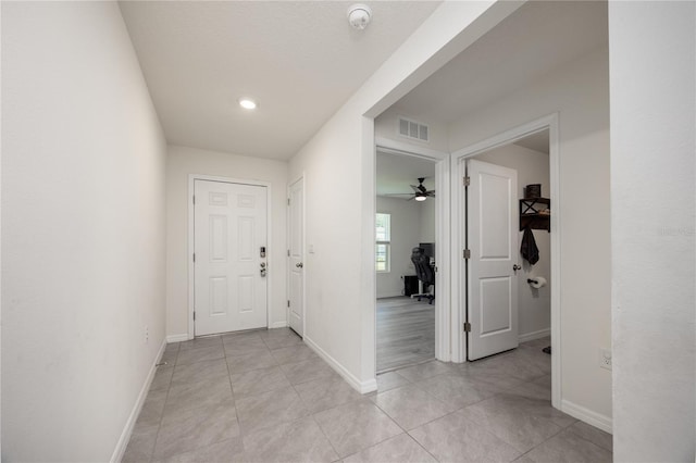hallway with baseboards, light tile patterned floors, and recessed lighting