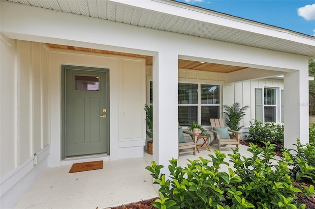 view of exterior entry featuring board and batten siding and covered porch