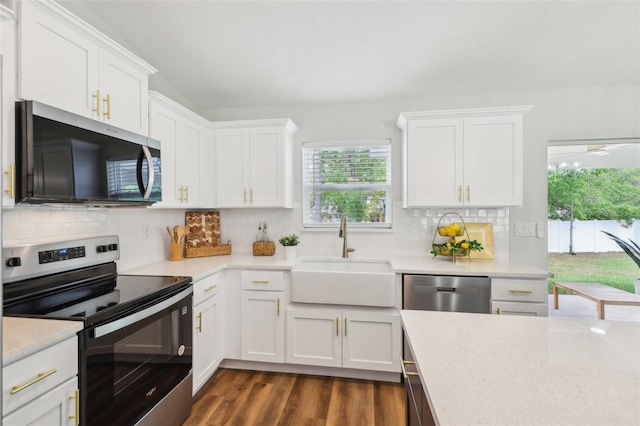 kitchen featuring appliances with stainless steel finishes, a sink, light countertops, white cabinetry, and backsplash