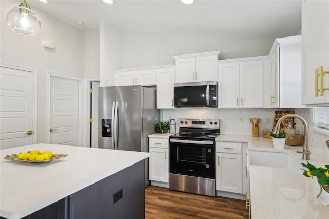 kitchen featuring appliances with stainless steel finishes, lofted ceiling, a sink, tasteful backsplash, and white cabinets