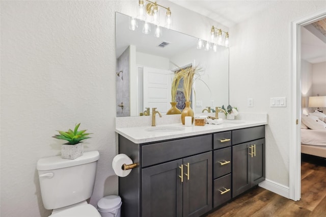 bathroom featuring toilet, connected bathroom, wood finished floors, double vanity, and a shower