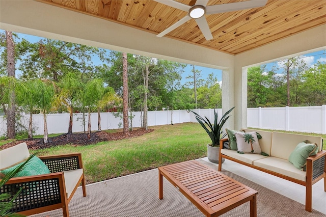 sunroom featuring outdoor lounge area, ceiling fan, and view of wooded area