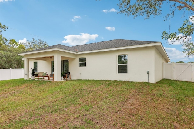 rear view of property featuring a gate, stucco siding, a patio, and an outdoor hangout area