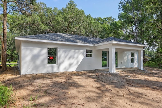 back of property featuring stucco siding, roof with shingles, and a patio area