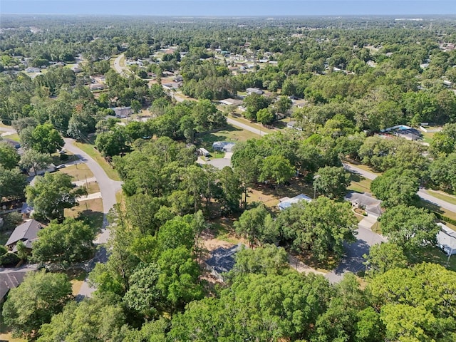 aerial view of property and surrounding area with nearby suburban area and a heavily wooded area