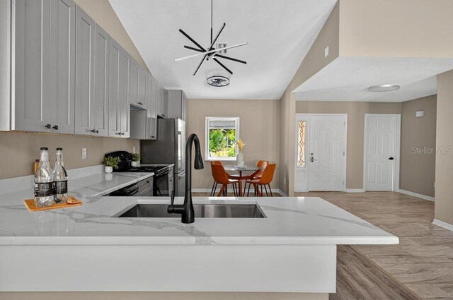 10545 Parkway Dr, Clermont, FL 34711 - kitchen featuring black / electric stove, light stone counters, baseboards, vaulted ceiling, and a sink