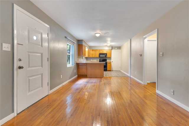12046 SE 135th Ave, Ocklawaha, FL 32179 - kitchen with stove, black microwave, a peninsula, light wood-style flooring, and baseboards