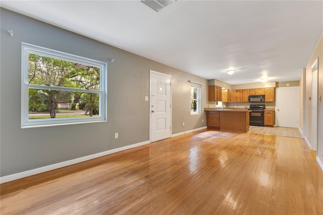 12046 SE 135th Ave, Ocklawaha, FL 32179 - kitchen featuring black appliances, a peninsula, brown cabinets, open floor plan, and light wood finished floors