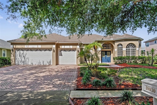 10030 Chatham Oaks Ct, Orlando, FL 32836 - view of front of home with stucco siding, decorative driveway, french doors, and a garage