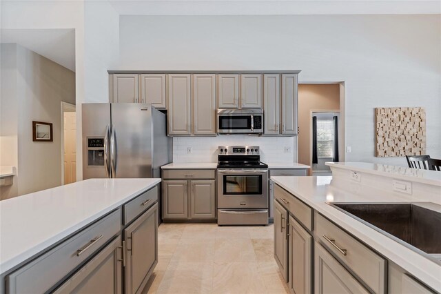 10030 Chatham Oaks Ct, Orlando, FL 32836 - kitchen featuring stainless steel appliances, gray cabinetry, light countertops, and backsplash