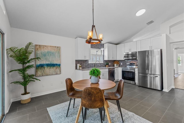 25 Reflections Village Dr, Ormond Beach, FL 32174 - dining area featuring healthy amount of natural light, lofted ceiling, dark tile patterned floors, a chandelier, and baseboards