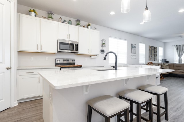 200 Summershore Dr, Auburndale, FL 33823 - kitchen with appliances with stainless steel finishes, open floor plan, light wood-style flooring, white cabinets, and recessed lighting