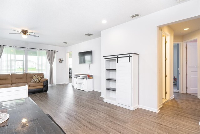 200 Summershore Dr, Auburndale, FL 33823 - living room featuring ceiling fan, wood finished floors, baseboards, a barn door, and recessed lighting