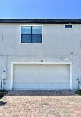 145 Kenny Blvd, Haines City, FL 33844 - rear view of property featuring an attached garage and decorative driveway