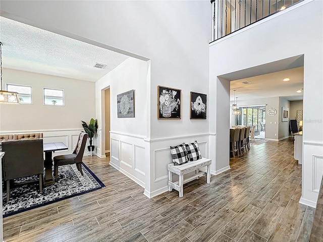 dining area with wood finished floors, a wainscoted wall, a chandelier, a decorative wall, and baseboards