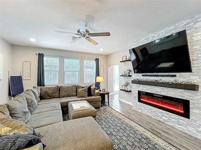 living room with a fireplace, wood finished floors, ceiling fan, and a textured ceiling