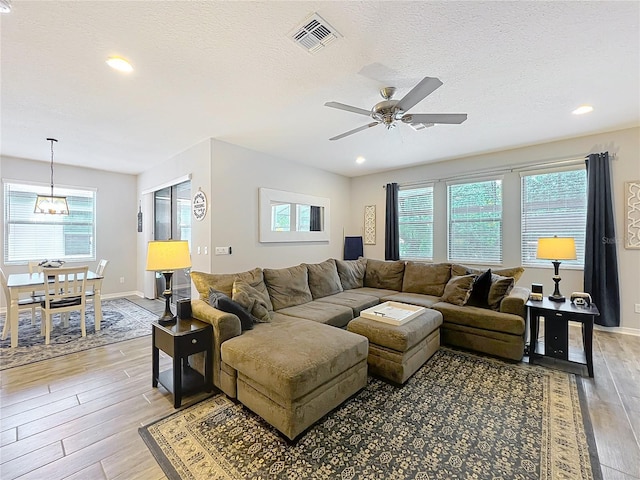 living area featuring light wood-style flooring, healthy amount of natural light, a ceiling fan, a textured ceiling, and recessed lighting