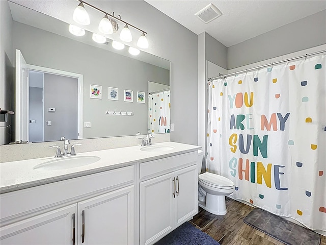 bathroom with wood finished floors, toilet, double vanity, and a shower with shower curtain